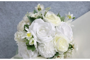 Close-up of white roses and pompon mums in a realistic bridal bouquet with green leaves