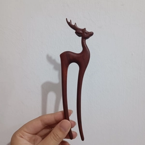 Detail of hand-carved sandalwood hair pin in a unique deer shape with brown finish