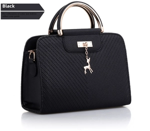 Detail of black quilted handbag featuring a golden giraffe charm and metal arc handle