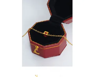 Detail of a gold square bead necklace with a red heart in a red octagonal jewelry box