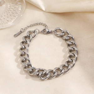 Polished silver stainless steel Cuban link bracelet with lobster clasp on silk background