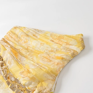 Detailed close-up of yellow floral print fabric with ruched texture and side metal chain link