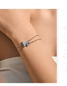 Detail of a S925 silver double-layer bracelet featuring a light blue butterfly pendant on wrist