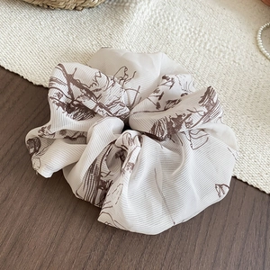 Detailed texture of off-white scrunchie with brown floral print on a mixed background