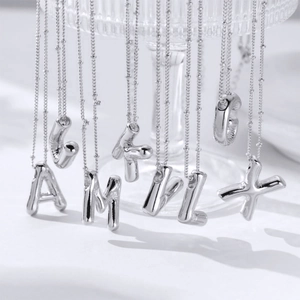 Silver balloon style alphabet pendant necklaces with mirror finish on glass display