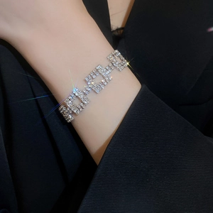 Close-up of a silver bracelet featuring square links with sparkling crystals on a wrist