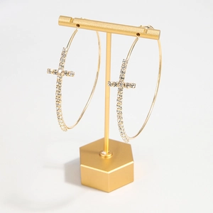 Gold hoop earrings with shimmering diamond-set cross charms on elegant display stand
