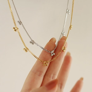 Close-up of delicate gold and silver cherry pendant necklaces on model hand