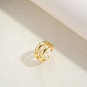 Detail of 14K gold plated double-layer open ring on a textured cream surface