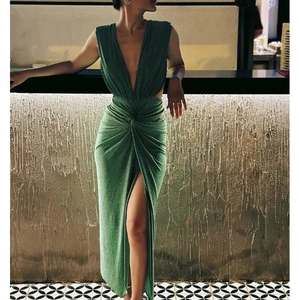 Detail of dark green shimmering fabric with waist knot and high slit on evening dress