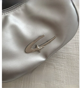 Macro detail of silver oil wax leather shoulder bag featuring a metallic G-star logo