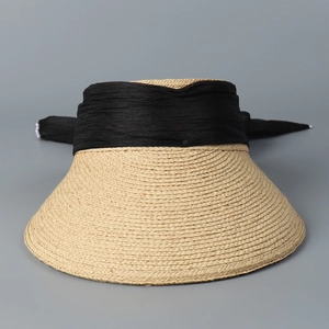 Detail view of khaki straw sun hat with black pleated fabric band and pearl accents