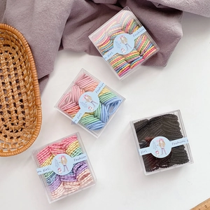 Detailed view of candy-colored kids hair ties in transparent square box packaging
