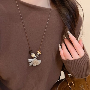 Detail of ginkgo leaf pendant on long beaded wax cord necklace for autumn outfits