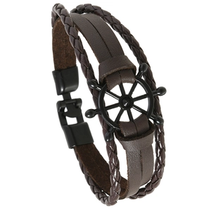 Detailed view of brown leather braided bracelet featuring a black metal rudder charm and clasp