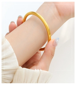 Close-up of a matte gold geometric bangle bracelet worn on a wrist for a luxury look
