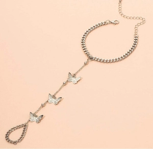 Détail du bracelet-bague argenté avec pendentifs papillon, maillons et fermoir mousqueton