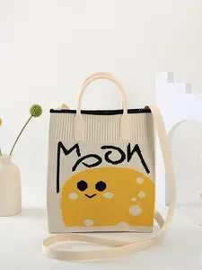 Detail of knit tote bag with MOON text and yellow smiling moon face embroidery