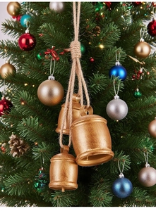 Rustic metal Christmas bells on jute rope hanging on a decorated festive tree branch