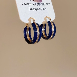 Detailed view of gold-trimmed deep blue enamel hoop earrings on a display card