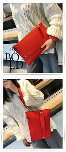 Detail van rode enveloppe clutch met lychee patroon, metalen noppen en polsband