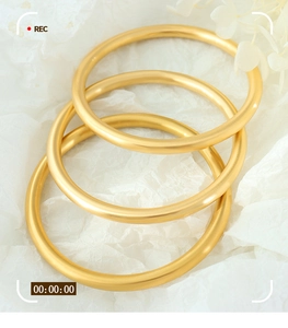 Detailed macro view of three matte gold geometric bangles with a brushed metal texture finish