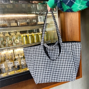 Detail of classic black and white gingham canvas tote bag in a casual lifestyle setting