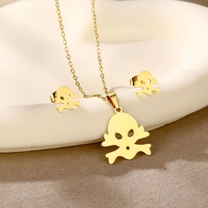 Macro shot of gold skull necklace and earring set in a ceramic display bowl