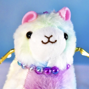 Close-up of rainbow cat plush toy with pearl necklace and soft pastel fur texture