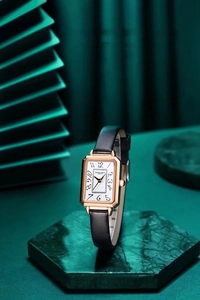 Detail of a square gold watch with white dial on green marble for a vintage luxury feel