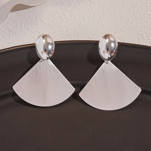 Macro view of silver fan-shaped earrings with polished and brushed metal textures