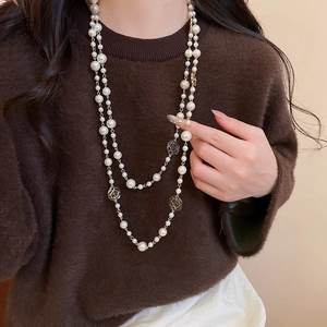 Detail of double-layer gold pearl necklace with hollow camellia flower pendants