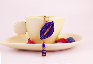 Detail of blue rhinestone lips and lipstick keychain hanging on a white cup