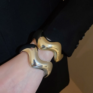 Dettaglio di bracciali a onde spessi in oro e argento sul polso di una modella