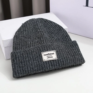 Dark grey knitted beanie featuring a white woven patch on the front, high-quality knit texture