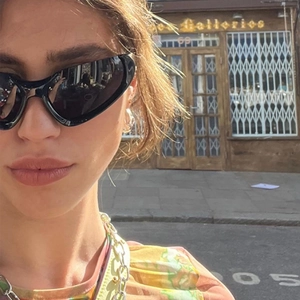 Outdoor street style model wearing black wrap-around Y2K sunglasses in retro fashion