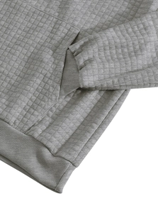 Close-up of grey waffle knit fabric hoodie with ribbed cuffs and pocket stitching details