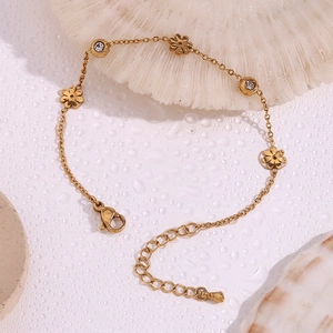 Detail view of 18K gold plated flower bracelet with white zircon on wet textured background