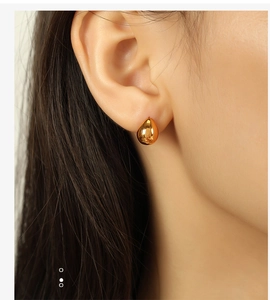 Macro shot of gold water drop stud earrings worn by a model for minimalist daily style