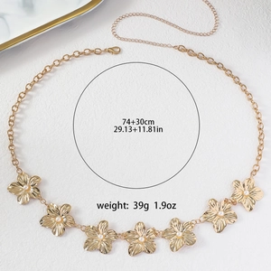 Detailed overhead shot of gold flower waist chain with pearls on white texture