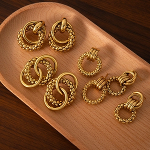 Detailed view of various gold-plated stainless steel earrings on a wooden tray