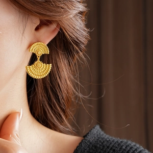 Détail des boucles d'oreilles vintage en forme d'éventail avec finition en métal doré