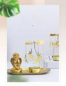 Close-up of golden spinning carousel candle holder with fairy pendants and oval tray