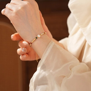 Gros plan d'un bracelet en perles avec détails dorés porté au poignet par un mannequin