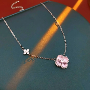 Detail of rose gold clover pendant with pink and white zircon on a green jewelry box