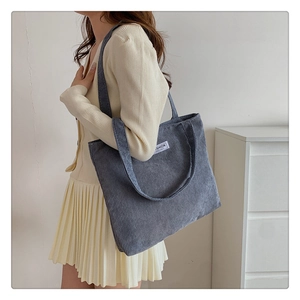 Detail of blue corduroy tote bag featuring a white Fashion label on the front