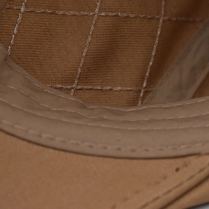 Macro shot of stitching on brown canvas beret with detailed mesh grid texture