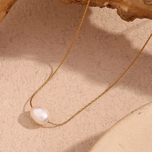 Macro shot of an oval white pearl pendant on a fine 18K gold-plated stainless steel chain