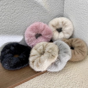 Set of 6 plush faux fur scrunchies in assorted neutral colors on a wooden base