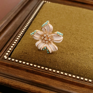 Détail du pendentif fleur vintage doré avec pétales blancs et perles de turquoise